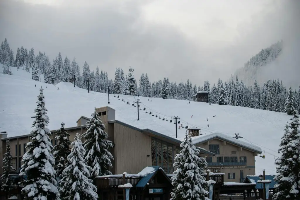 Scenic view of a snow-covered ski resort with skiers on the slope at Snoqualmie Pass.